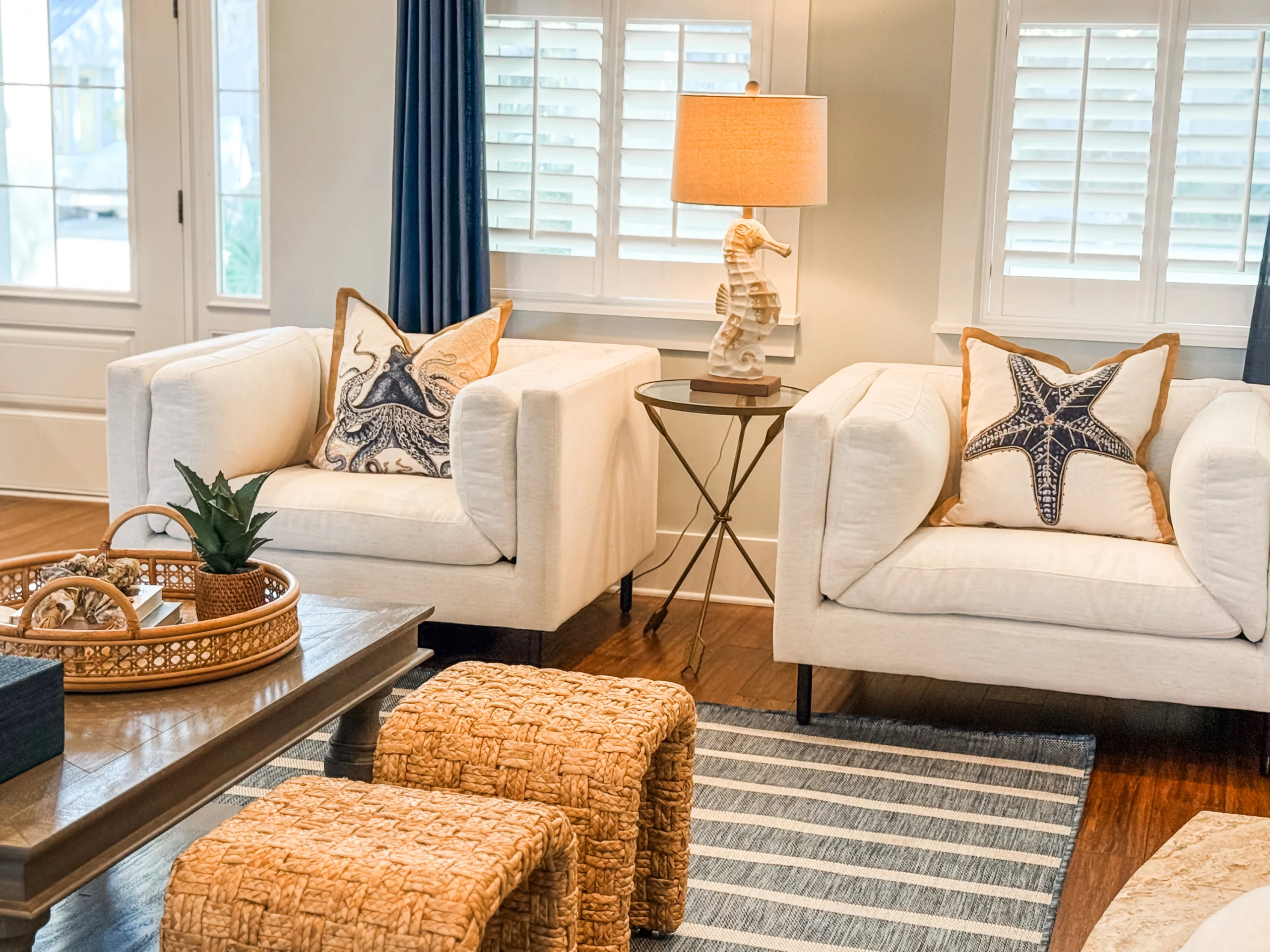 Coastal living room with white chairs, nautical pillows, and warm lighting at a Luxe Couples Retreat property.