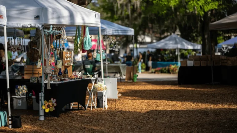 Outdoor artisan market with white tents, handmade bags, and crafts displayed on a sunny day