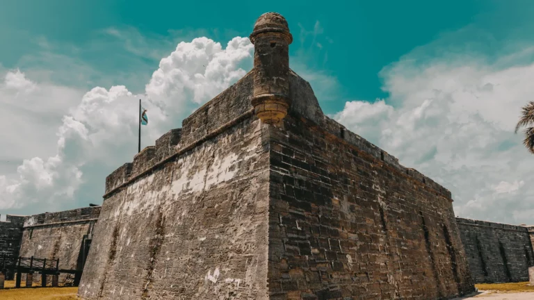 The historic stone walls and corner watchtower of Castillo de San Marcos in St. Augustine under a cloudy blue sky