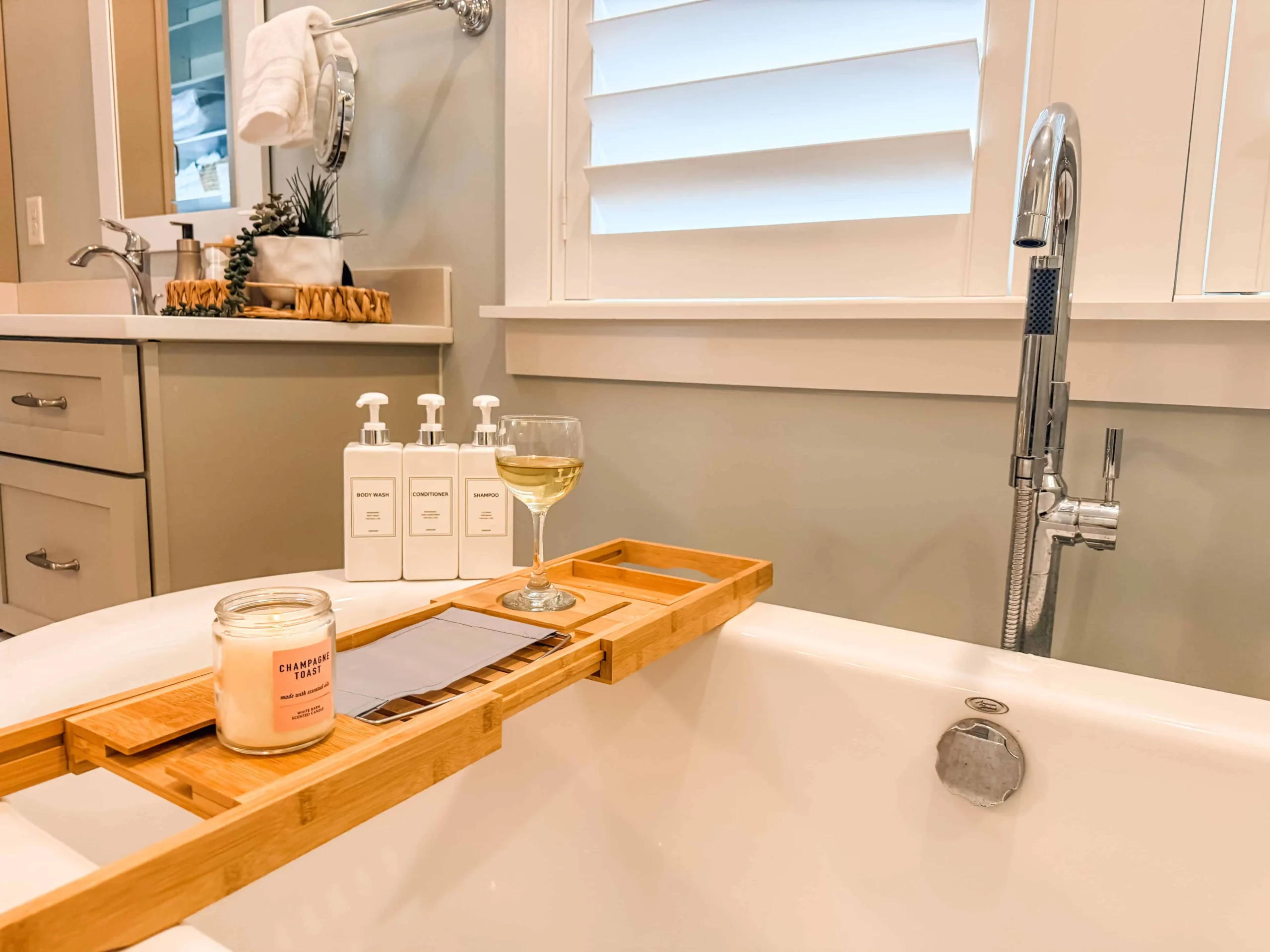 Luxury bathtub with bath amenities, candle, wine glass, and wooden tray at a Luxe Couples Retreat property.