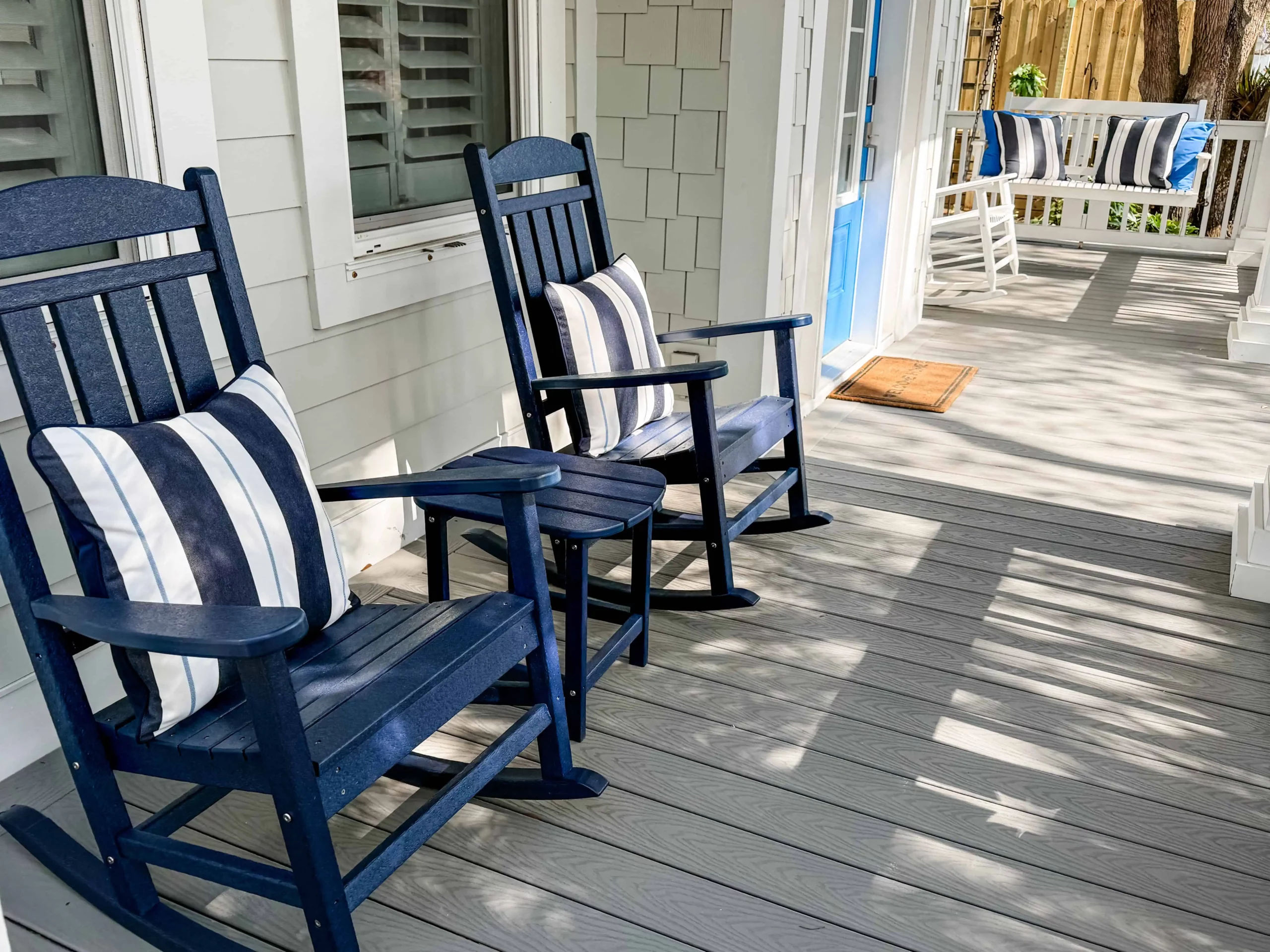 Front porch with blue rocking chairs, striped pillows, and a porch swing at a Luxe Couples Retreat property.