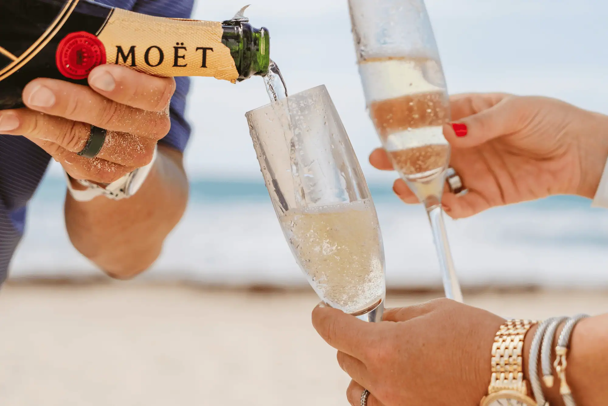 Champagne being poured into glasses on the beach during a romantic coastal getaway.