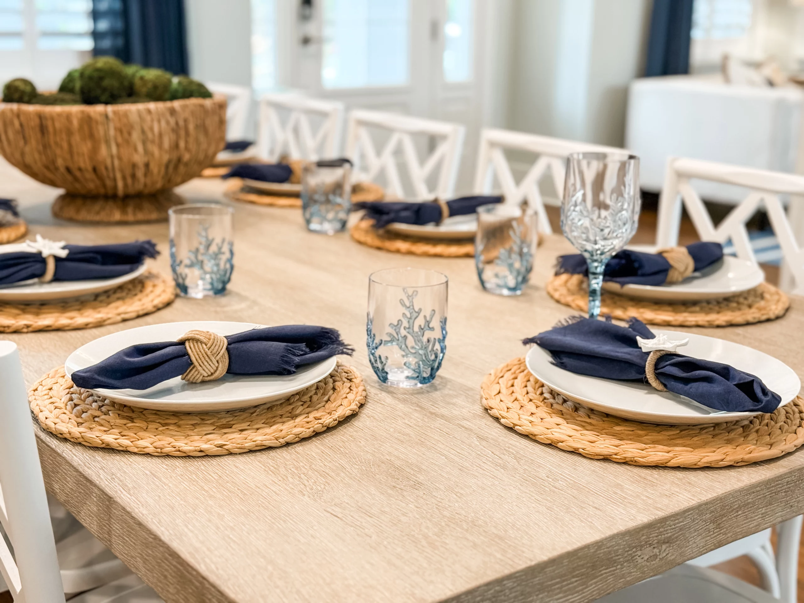 Dining table set with coastal place settings, navy napkins, woven placemats, and glassware at a Luxe Couples Retreat property.